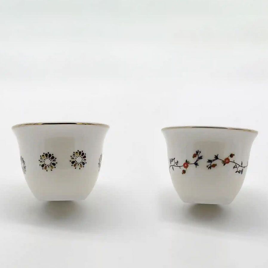 Two porcelain Arabic coffee cups featuring delicate floral and geometric motifs, displayed side by side