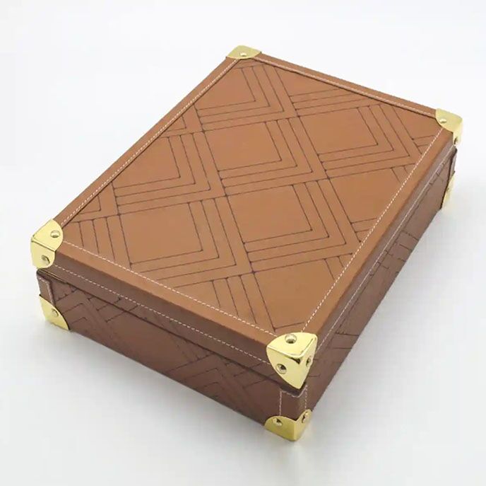 Brown leather date box featuring a geometric etched pattern and gold metal corners, opened to reveal premium dates
