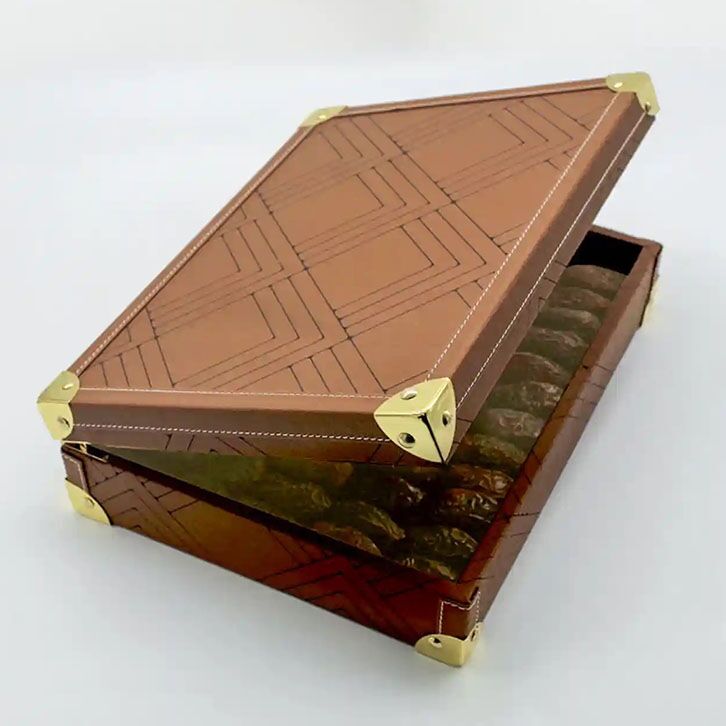Brown leather date box featuring a geometric etched pattern and gold metal corners, opened to reveal premium dates